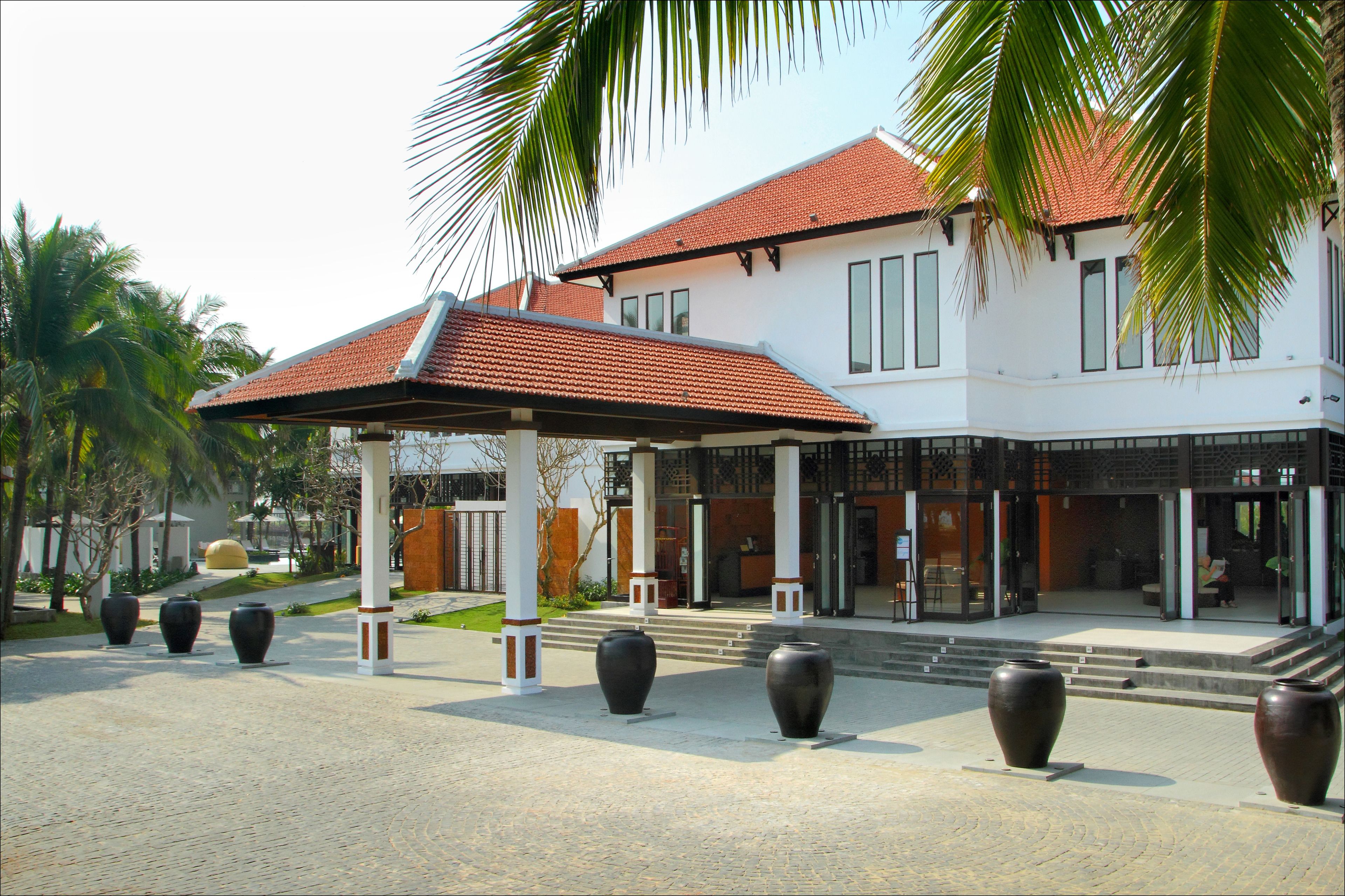 A modern building with a red-tiled roof, large windows, and a covered entrance area.