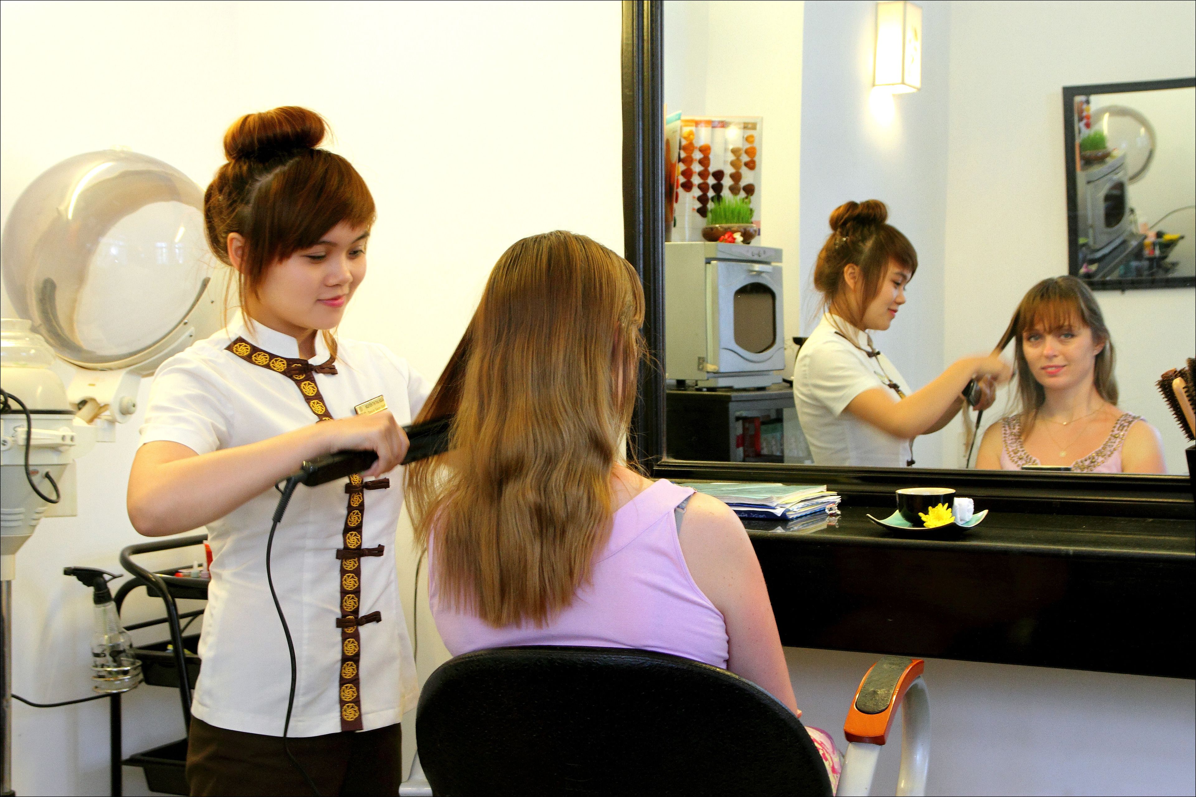 A hair salon interior with a mirror, hairdryer, and styling tools.