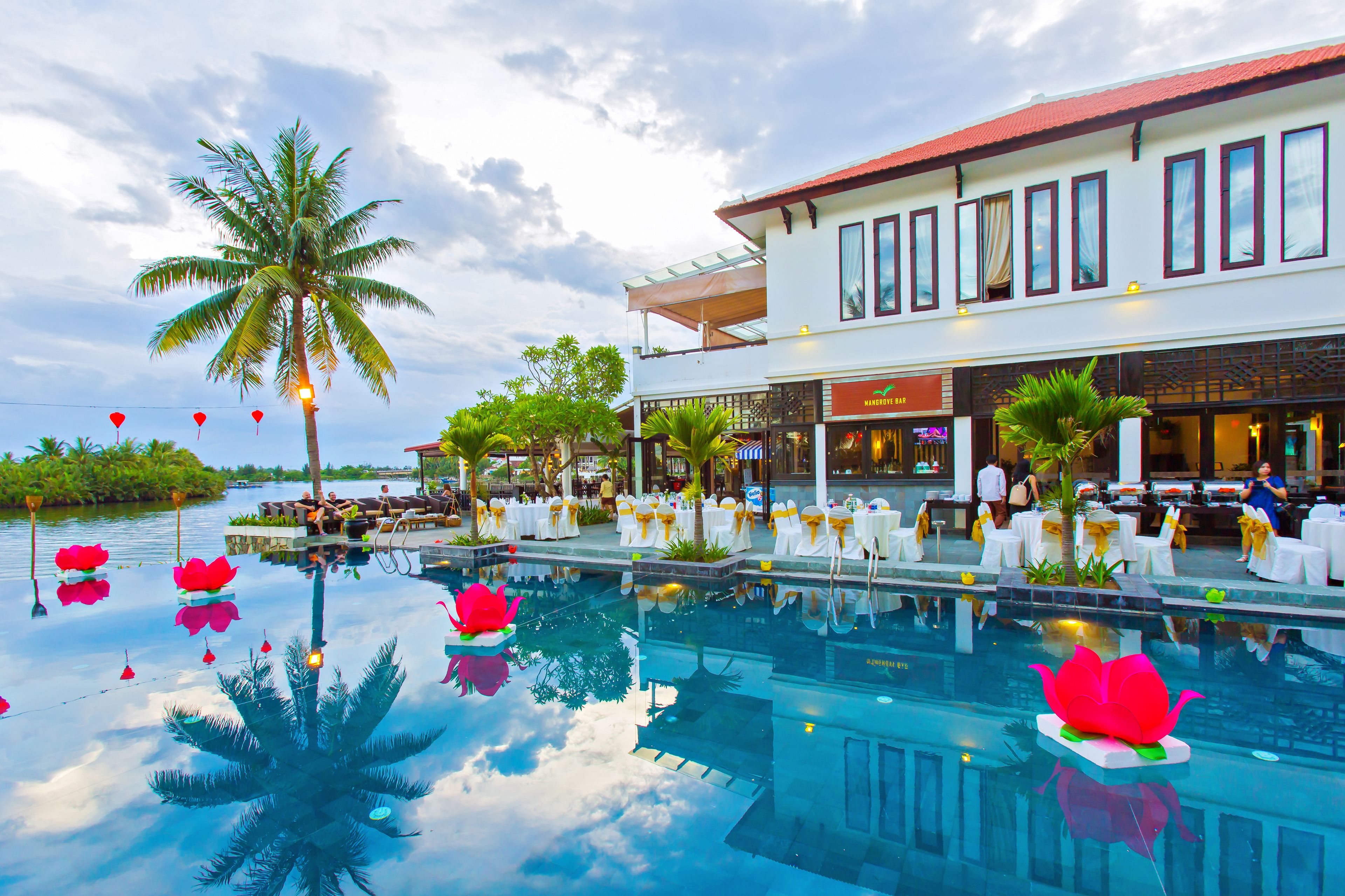 A hotel with a pool, palm trees, and a restaurant.