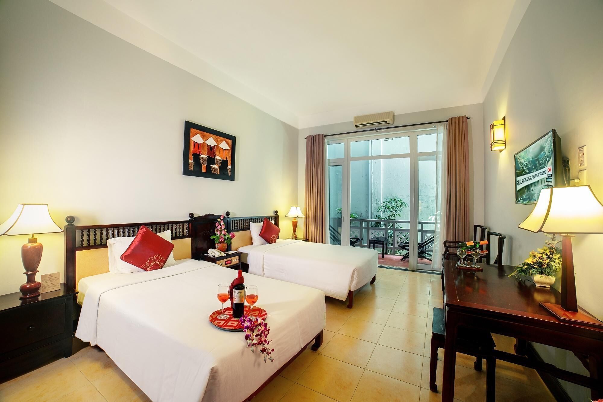 A hotel room with two beds, a dining table, and a balcony with a view.