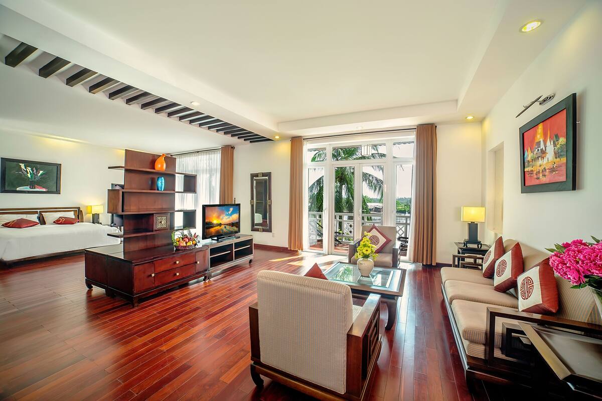 A spacious living room with a sofa, a coffee table, a TV, and a bookshelf.