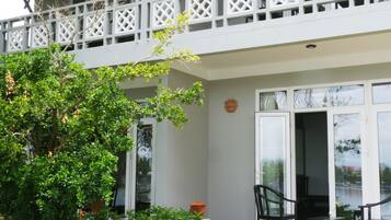 A two-story building with a balcony, a garden with a pathway, and a large potted plant.