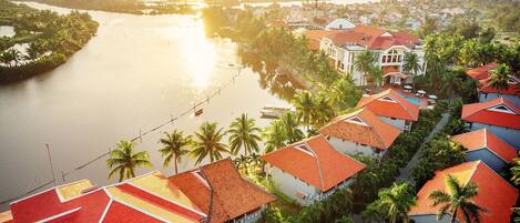A coastal residential area with houses featuring red-tiled roofs and palm trees.