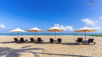 En privat strand, hvidt sand, liggestole, parasoller