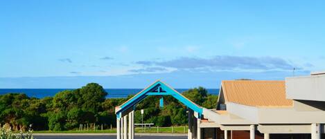 A building with a blue archway entrance, a road in front, and a view of the sea.