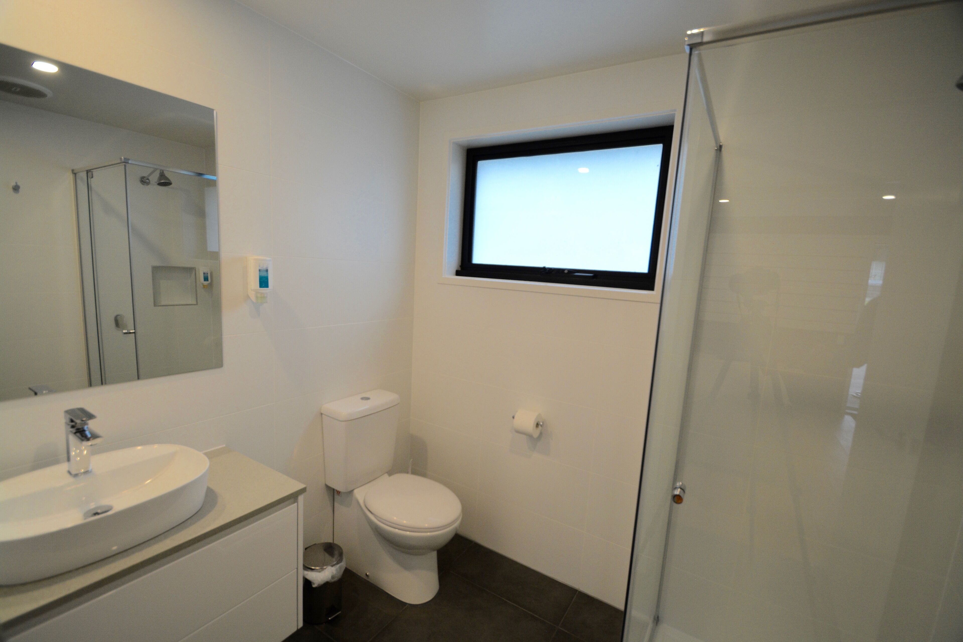 A modern bathroom with a sink, toilet, and shower.