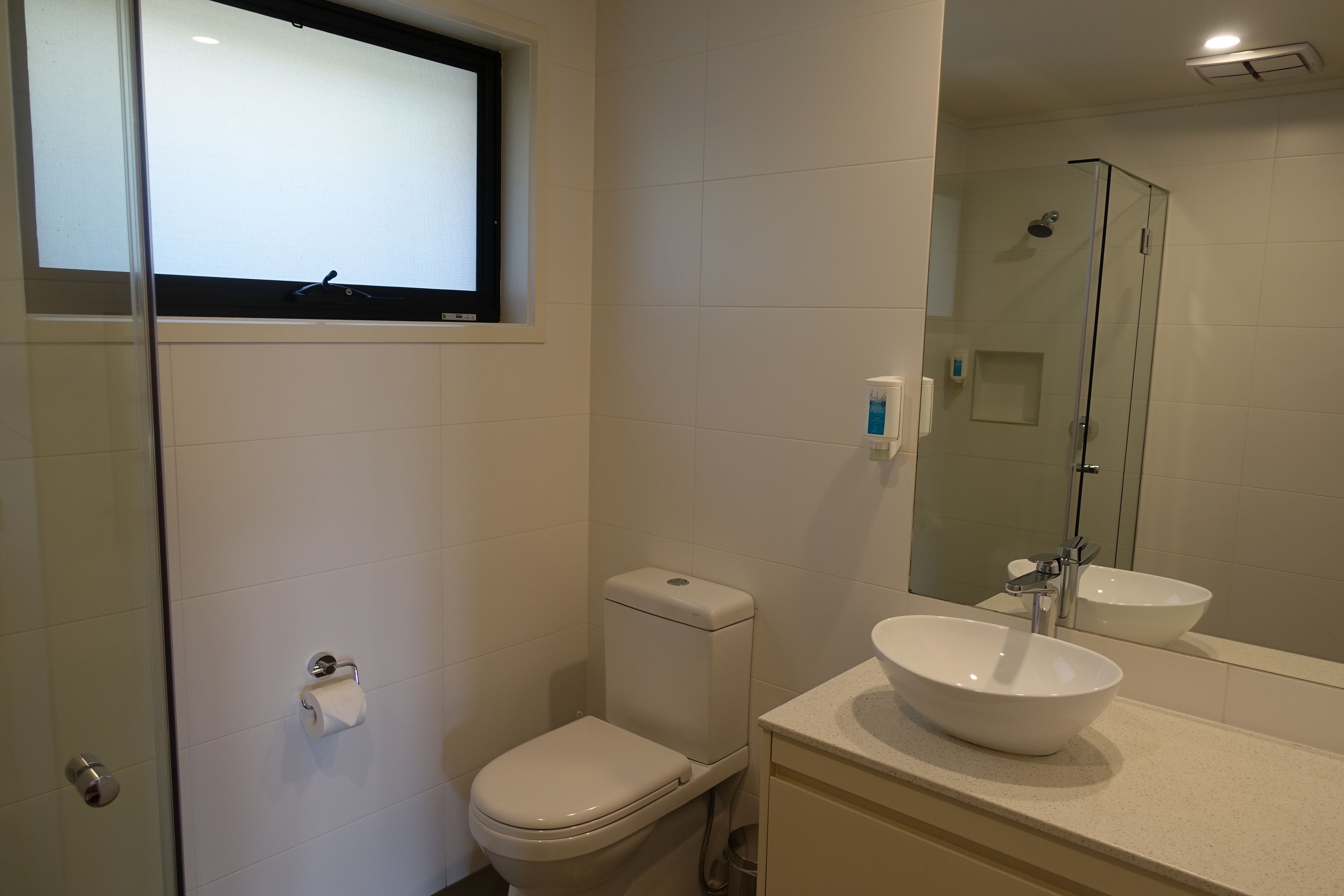 Un baño con inodoro, lavamanos y cabina de ducha de vidrio.