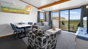 Una sala de estar moderna con comedor, ventanas amplias y un balcón con vistas.