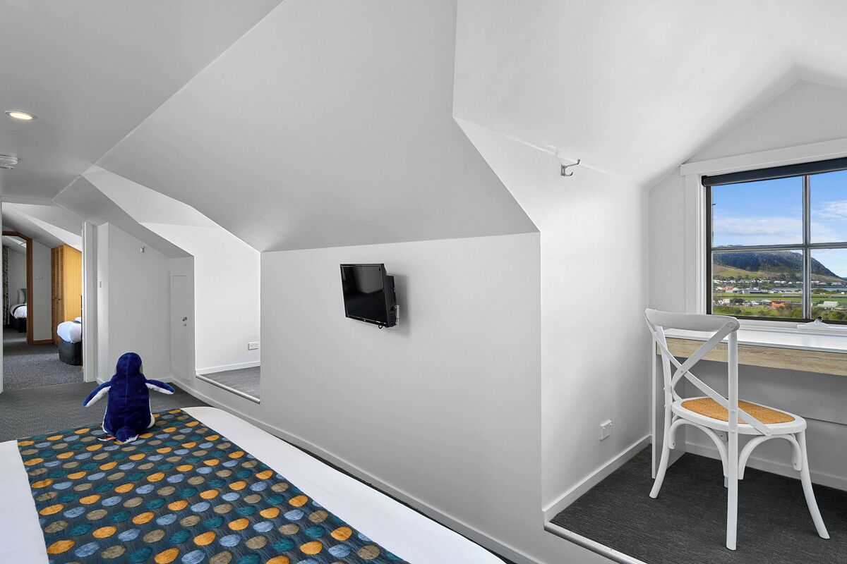 Quarto de hotel moderno com uma janela ampla, uma escrivaninha e um tapete estampado.