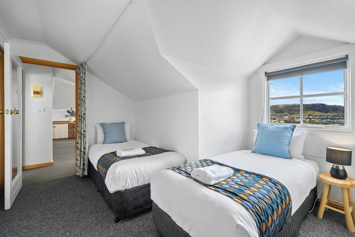 Ein modernes Hotelzimmer mit zwei Betten, einem großen Fenster mit Blick auf die Berge und einem separaten Badebereich.