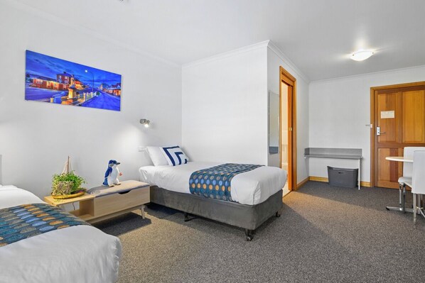 A modern hotel room with a large bed, a desk, and a chair. There is a painting on the wall and a small plant on the desk. - Stanley Seaview Inn (Stanley)