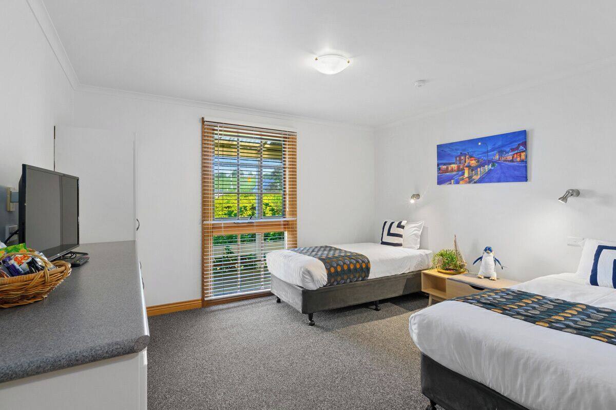 A hotel room with a bed, bedside table, lamp, and a painting on the wall.