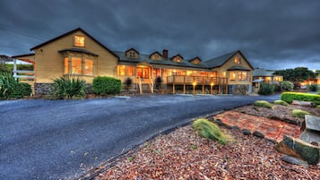 Stunning multi-story building with a grand entrance, covered porch, and beautifully landscaped garden.