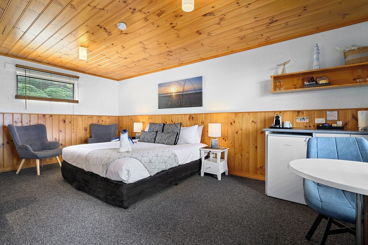 A bedroom with a bed, bedside tables, a desk, and a chair.