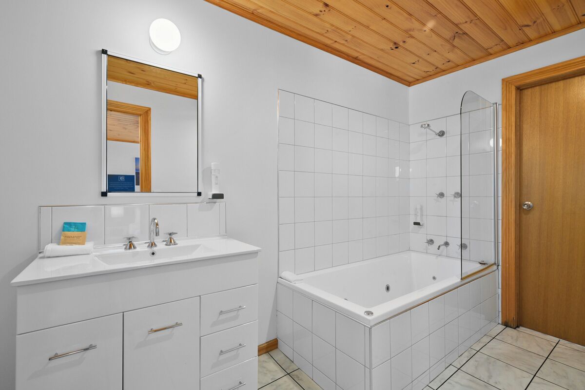 A modern bathroom with a large bathtub, a separate shower area, and a vanity with a mirror.