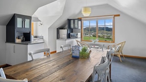 Una cocina moderna con zona de comedor, vistas al campo y techo inclinado.
