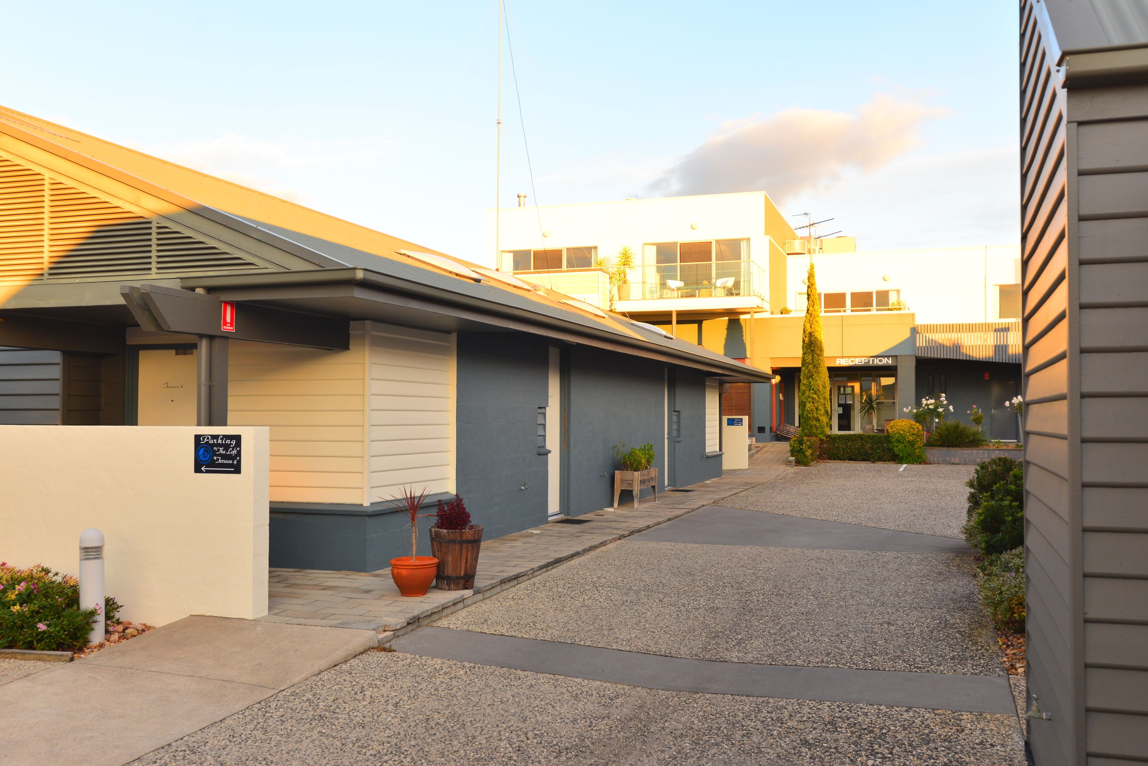 A row of motel buildings with a parking area in front.