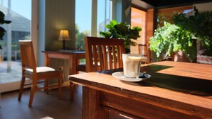Una mesa de madera con un vaso de leche y un plato, una silla de madera y una lámpara.