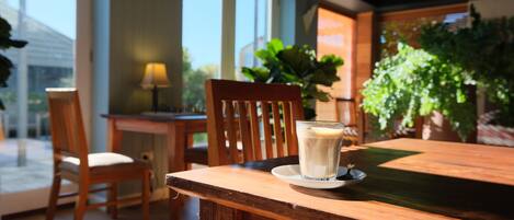 A wooden table with a glass of milk and a plate, a wooden chair, and a lamp.