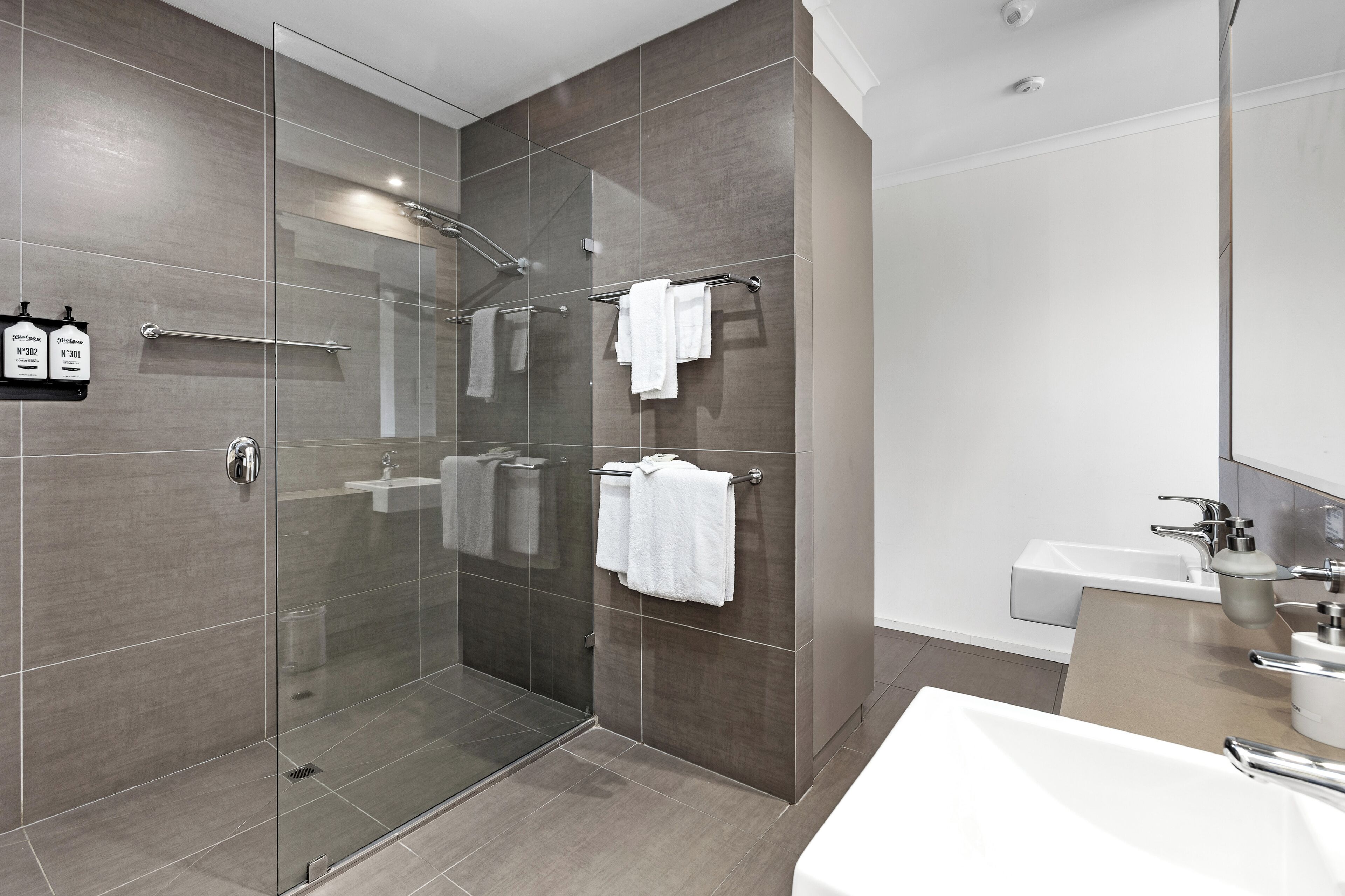 A modern bathroom with a glass-enclosed shower, a white sink, and a mirror.