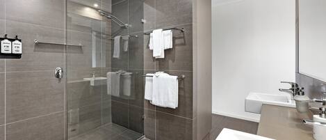 A modern bathroom with a glass-enclosed shower, a white sink, and a mirror.
