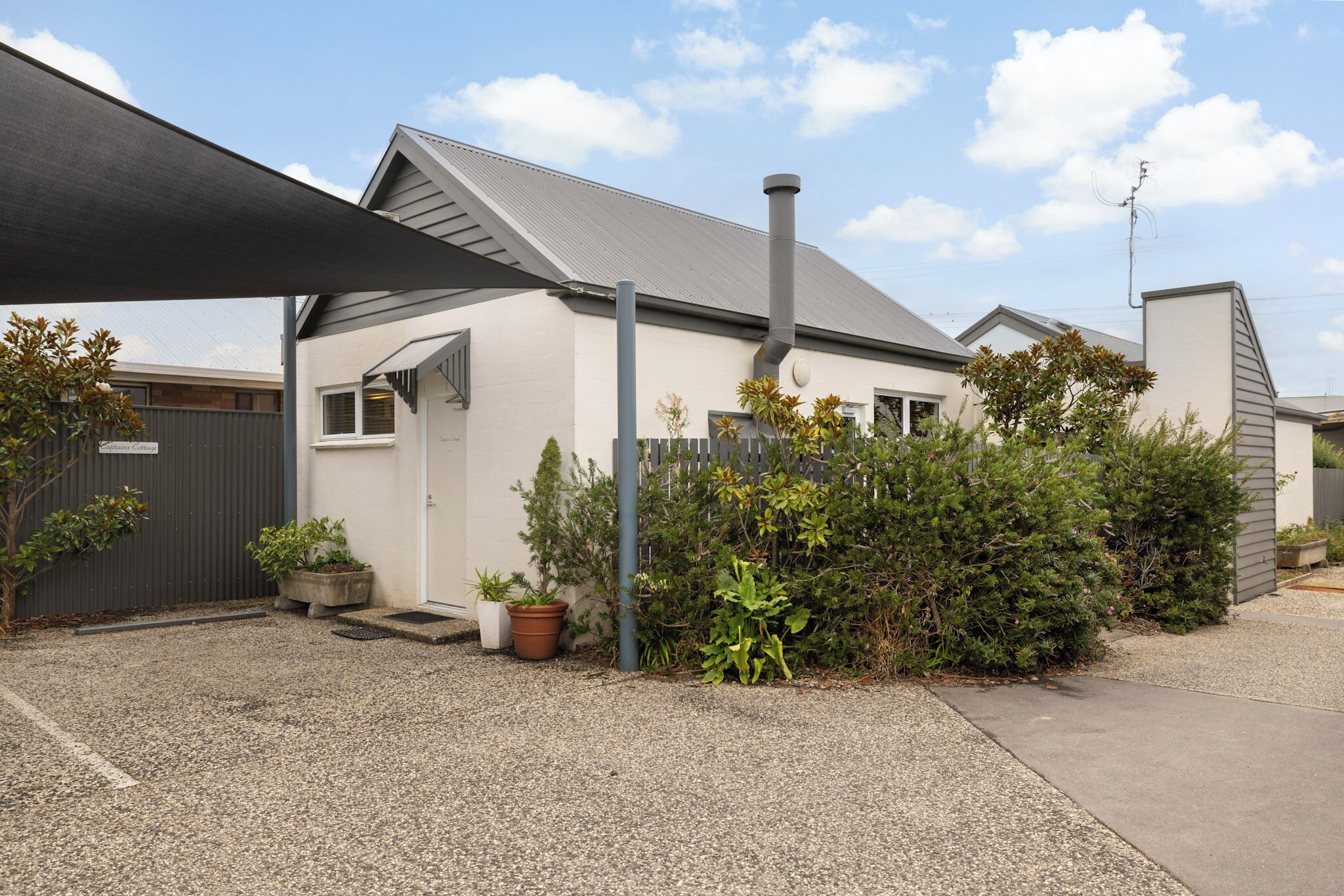 A residential building with a sloped roof, a chimney, and a covered driveway.