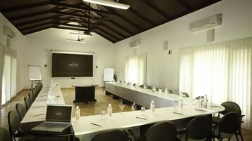 A conference room with a long table, chairs, a laptop, and a projector screen.