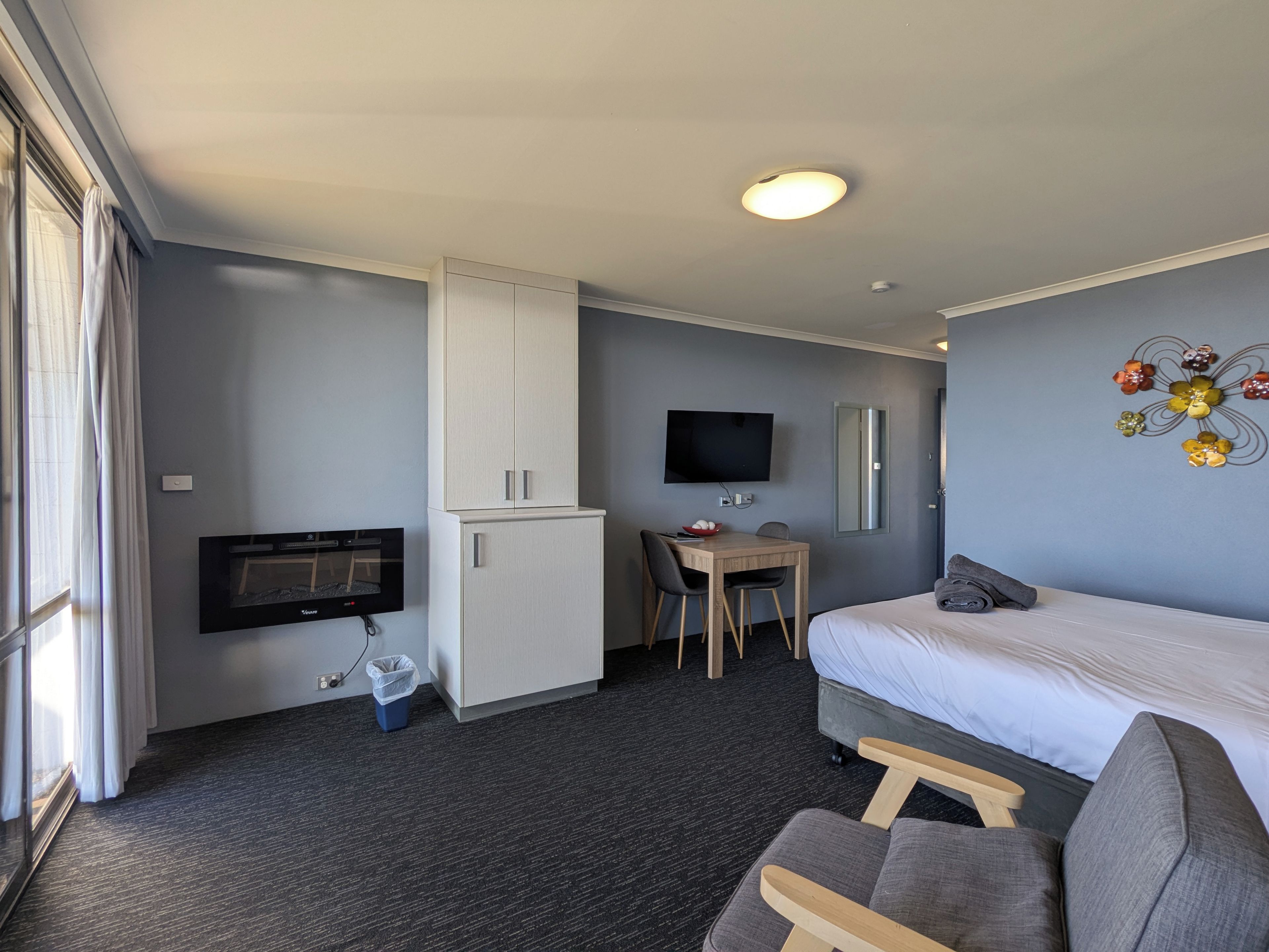 Une chambre d’hôtel équipée d’un lit, d’un bureau, d’une télévision, d’une armoire et d’une poubelle.