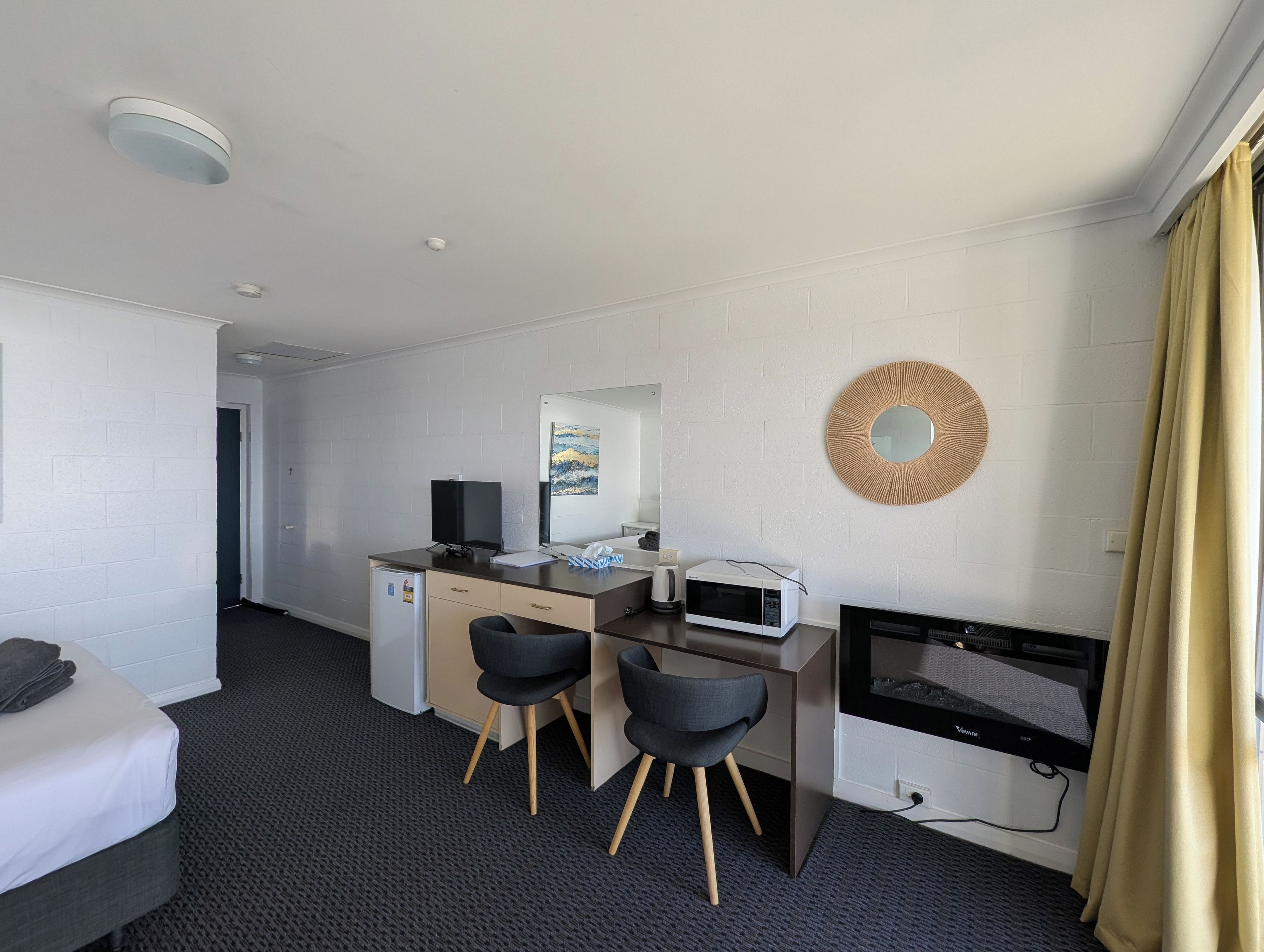 Una habitación de hotel con una cama, un escritorio con computadora, un microondas y un televisor.