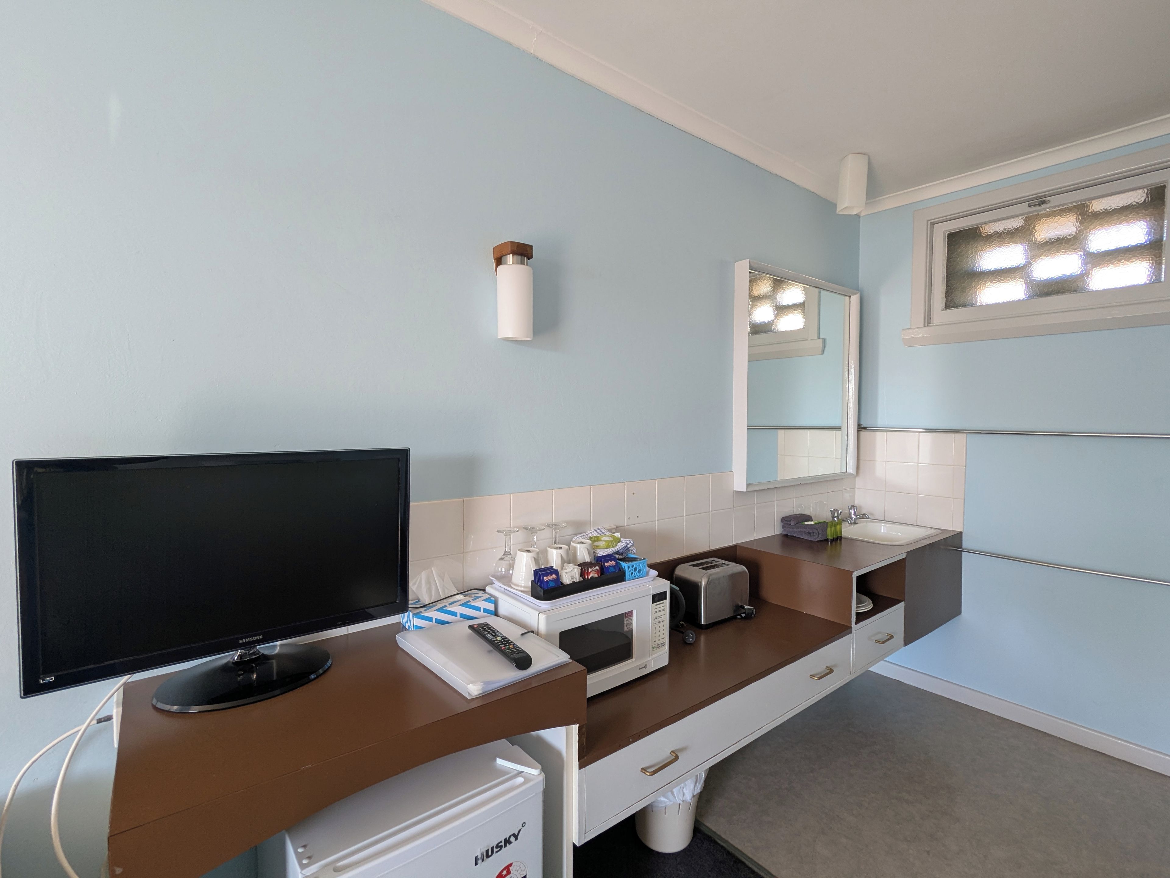 Un bagno moderno con TV a schermo piatto, forno a microonde, tostapane e lavabo con specchio sopra.