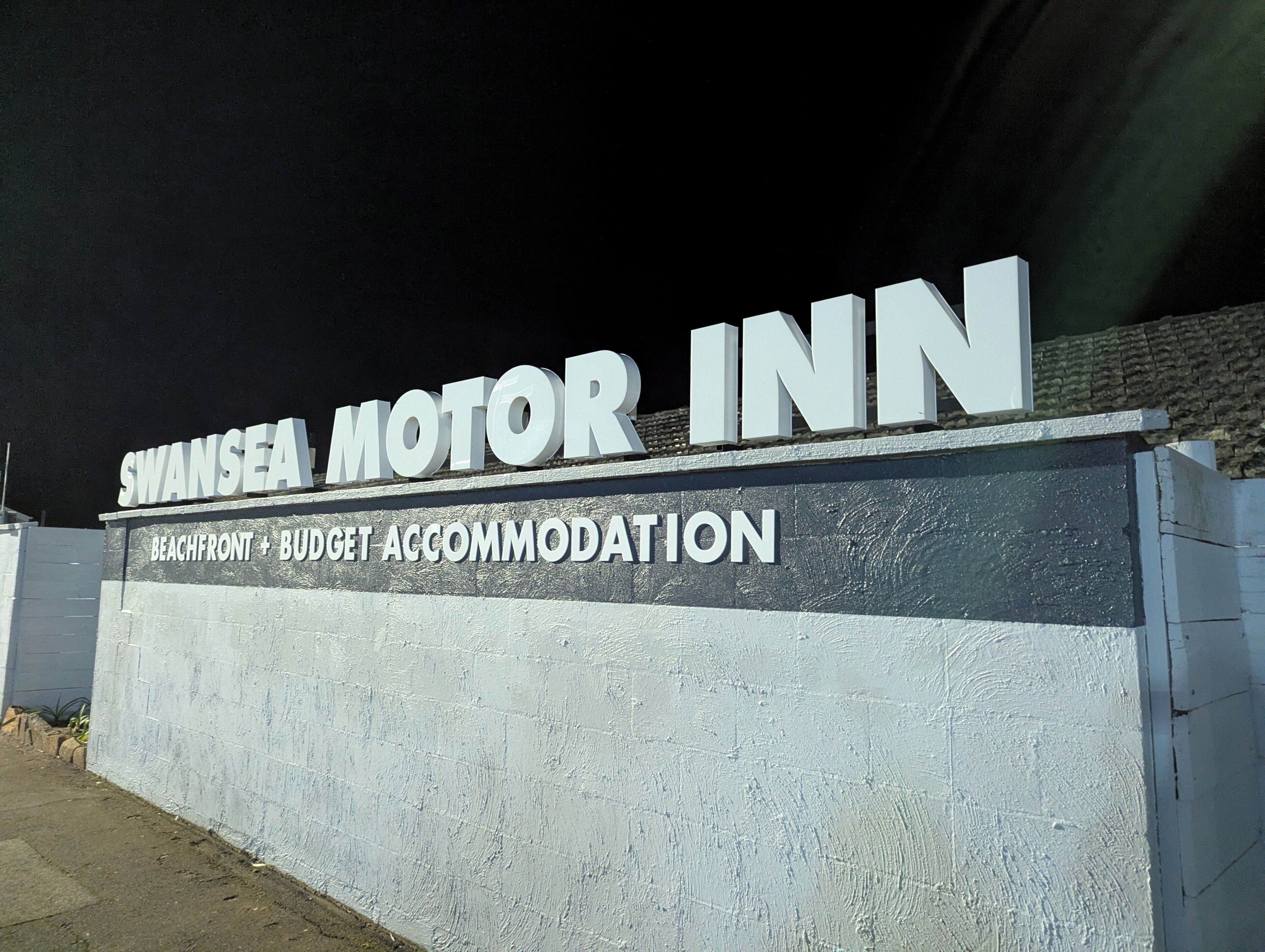 Indicador del Swansea Motor Inn, que mostra que és un allotjament econòmic i a peu de platja.