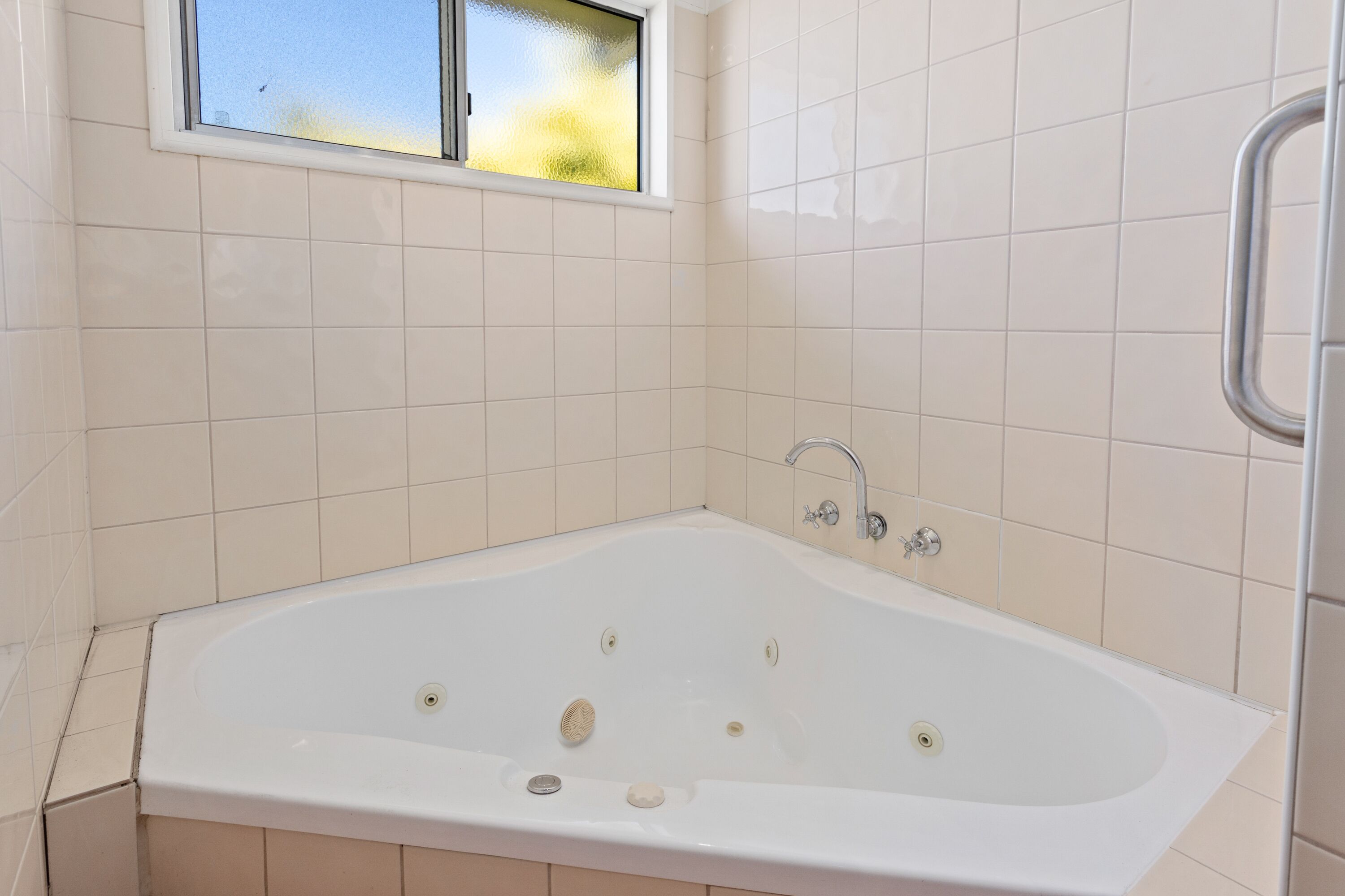 Un baño moderno con una bañera independiente, una ventana y paredes con azulejos.