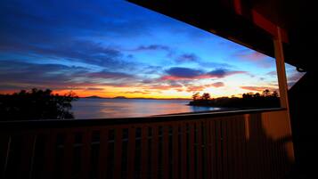 Un balcon donnant sur un coucher de soleil sur une étendue d’eau.