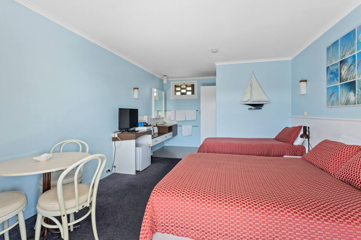 A hotel room with a bed, a desk, a chair, a TV, and a bathroom.