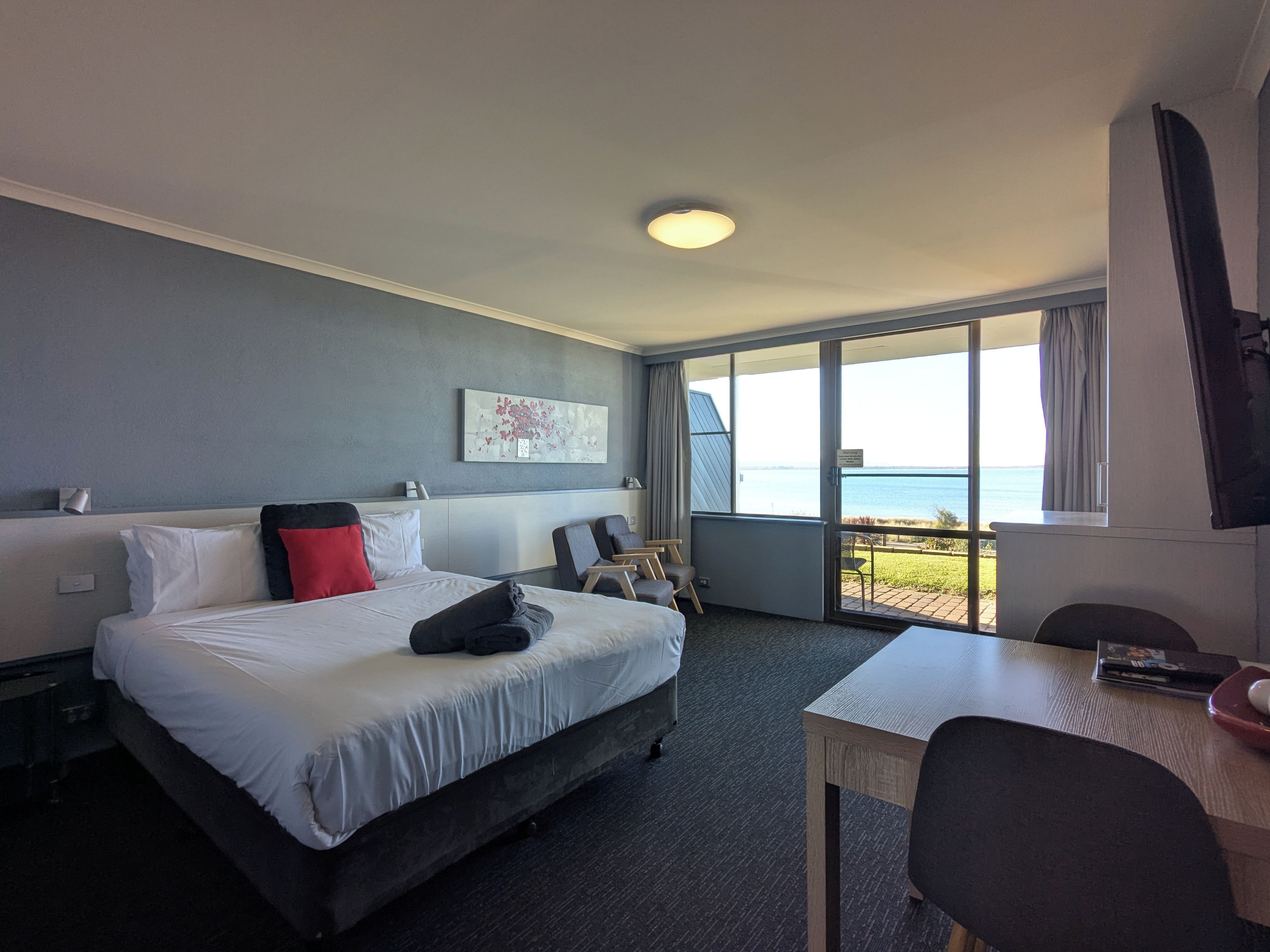 Una habitación de hotel con cama, escritorio y vista al mar.