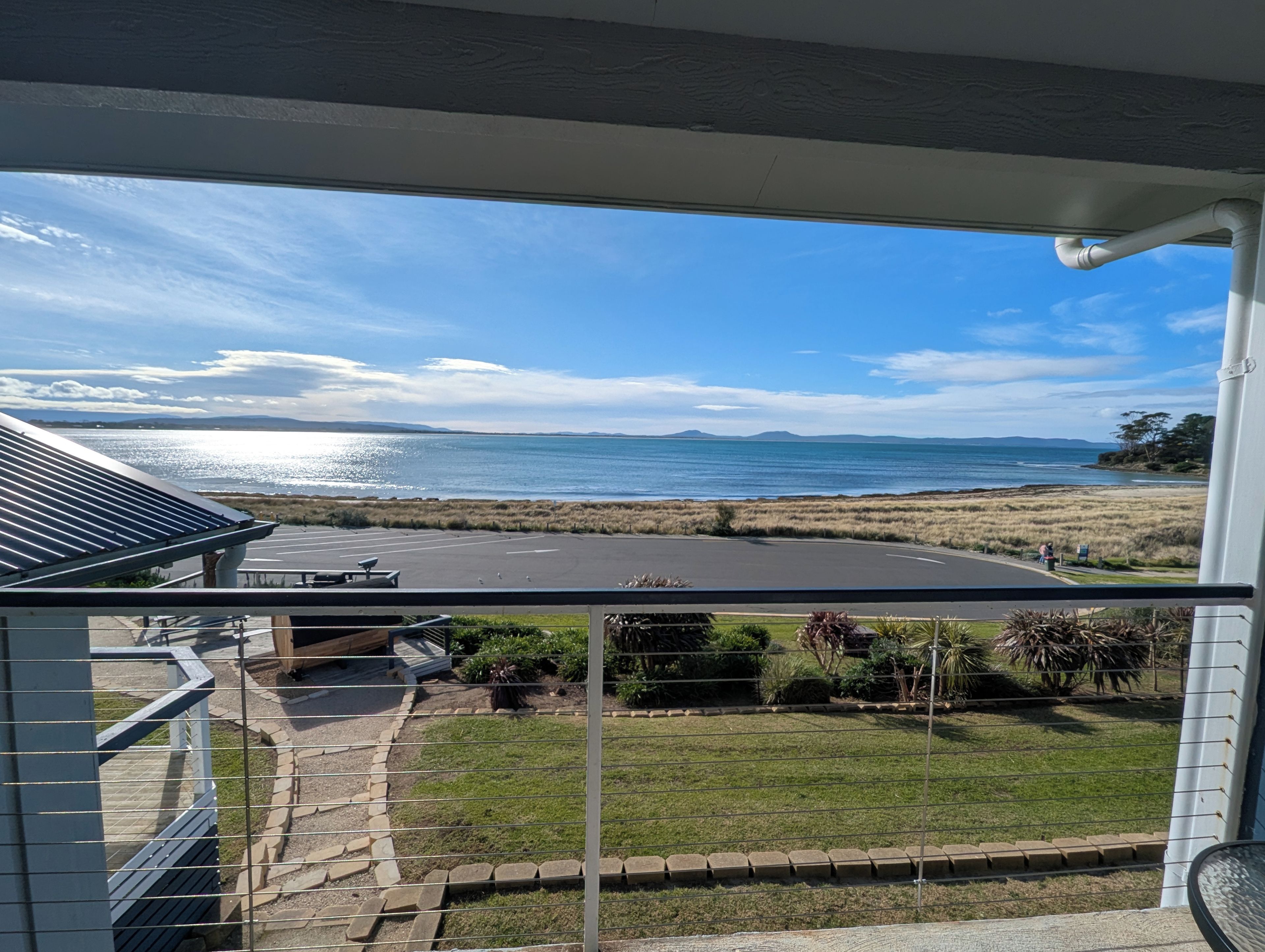 Vista desde un balcón sobre una playa con cielo despejado.