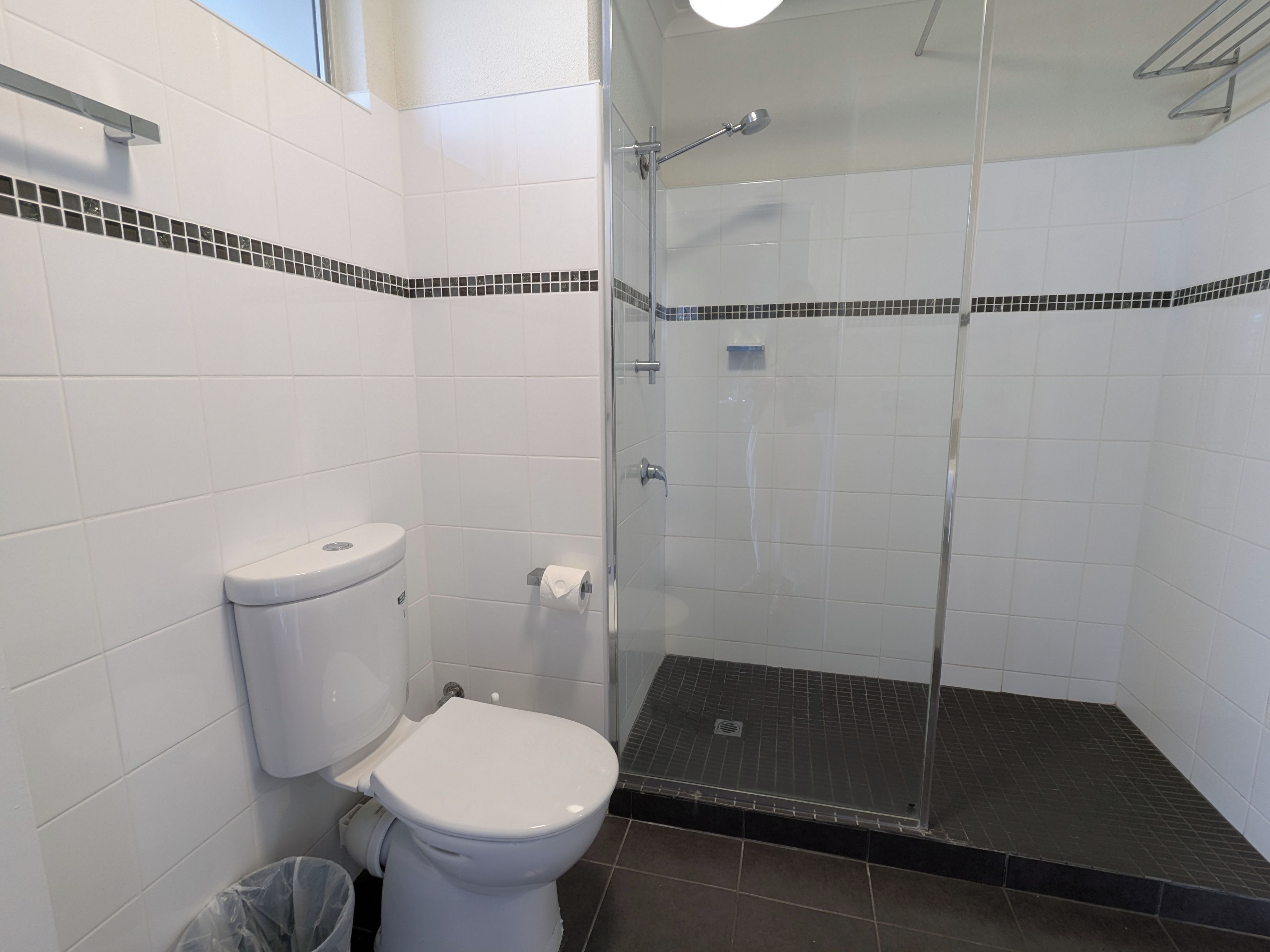 A bathroom with a toilet, a shower enclosure, and a tiled floor.