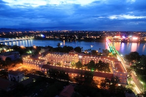 A large, historic building with multiple wings and a central courtyard, surrounded by a river and a bridge. - Hotel Saigon Morin (Hue)