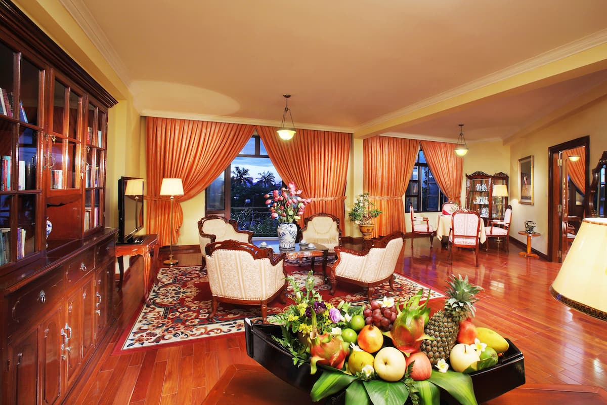 A spacious living room with a large wooden cabinet, a dining area with a table and chairs, and a fruit basket on the floor.