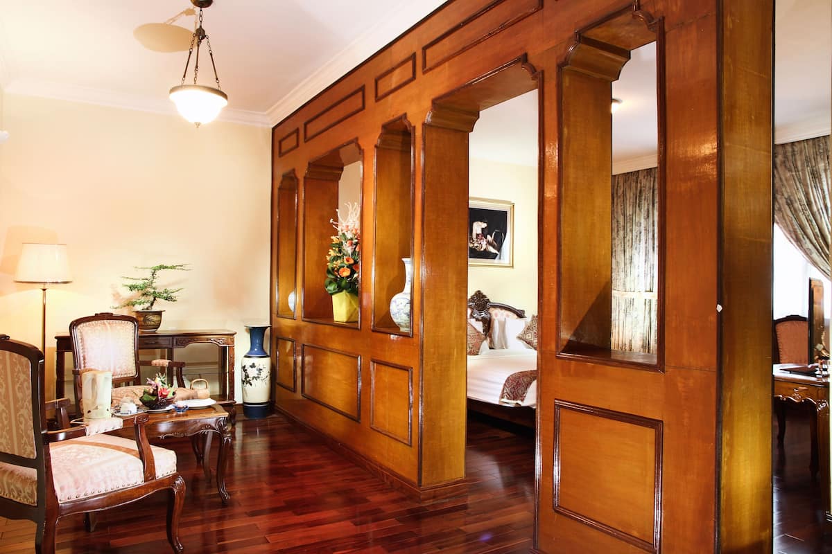 A room with a wooden partition, a bed with a headboard, a desk with a lamp, and a chair.