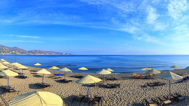 A beach with rows of sun loungers and umbrellas, a clear blue sky, and a calm sea. - Apollonia Beach Resort & Spa (Malevizi)