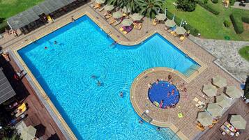A large rectangular swimming pool with a circular hot tub area, surrounded by lounge chairs and umbrellas.