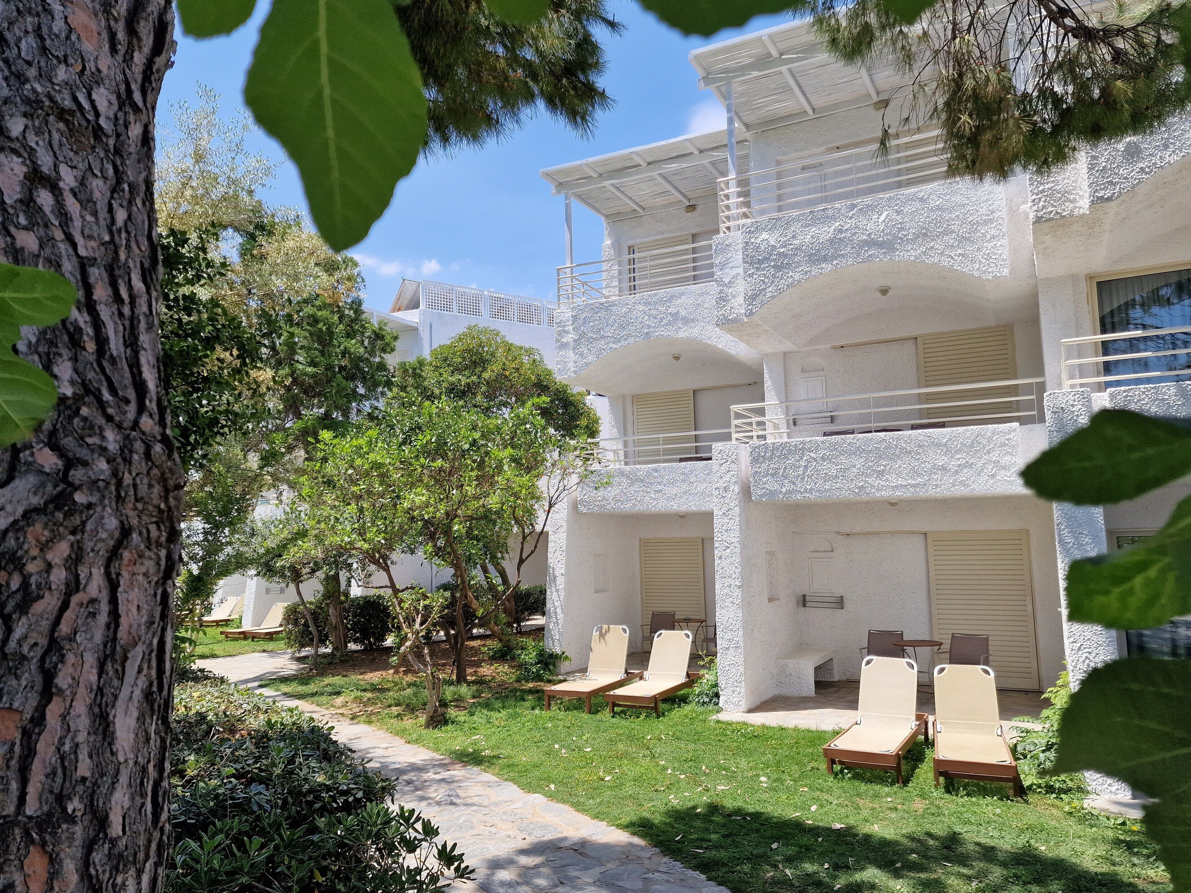 Un edificio de dos pisos con fachada blanca, varios balcones y zonas de estar al aire libre.
