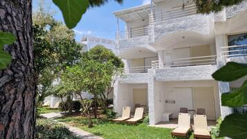 Un edificio de dos pisos con fachada blanca, varios balcones y zonas de estar al aire libre.
