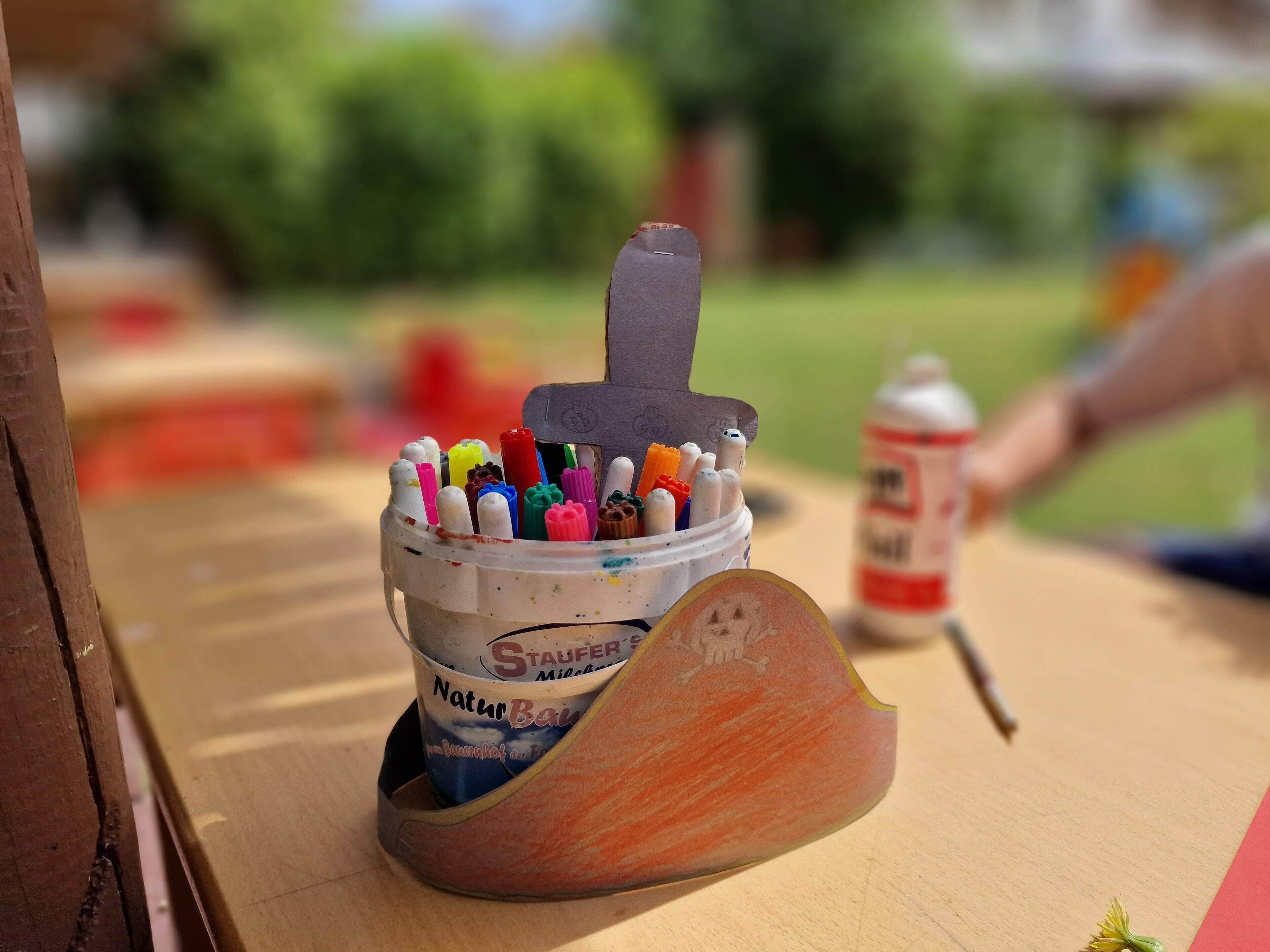 Un portalápices con una lata de pintura que contiene varios marcadores de colores.