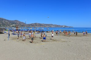A beach volleyball court with players, umbrellas, and beach chairs. - Apollonia Beach Resort & Spa (Malevizi)