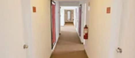 A narrow hallway with white walls and a beige carpet.