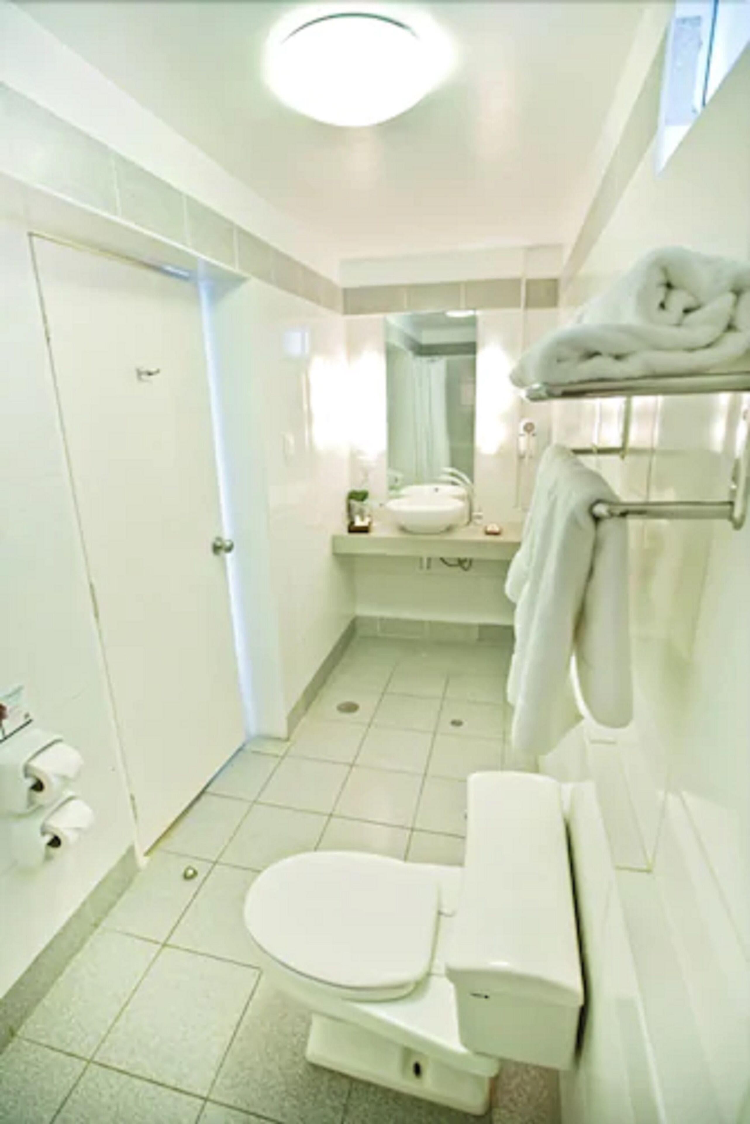 A small, clean bathroom with a toilet, sink, and towel rack.