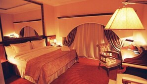 Ett hotellrum med en stor säng, en stol, ett skrivbord och en lampa.