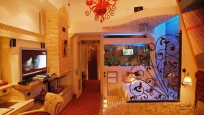 A cozy room with a television, a decorative wall, and a unique metal design on the right side. - Boutique Palace Hotel Baku (Baku)